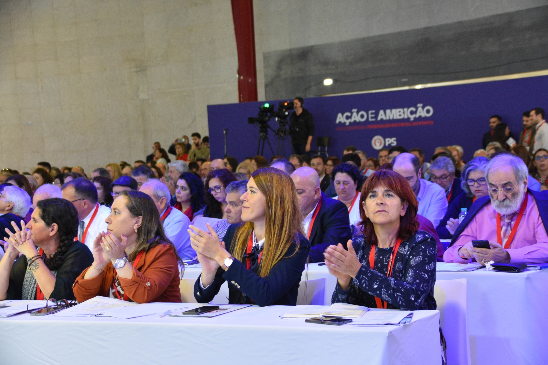 Participantes a assistir e a aplaudir numa mesa do congresso.